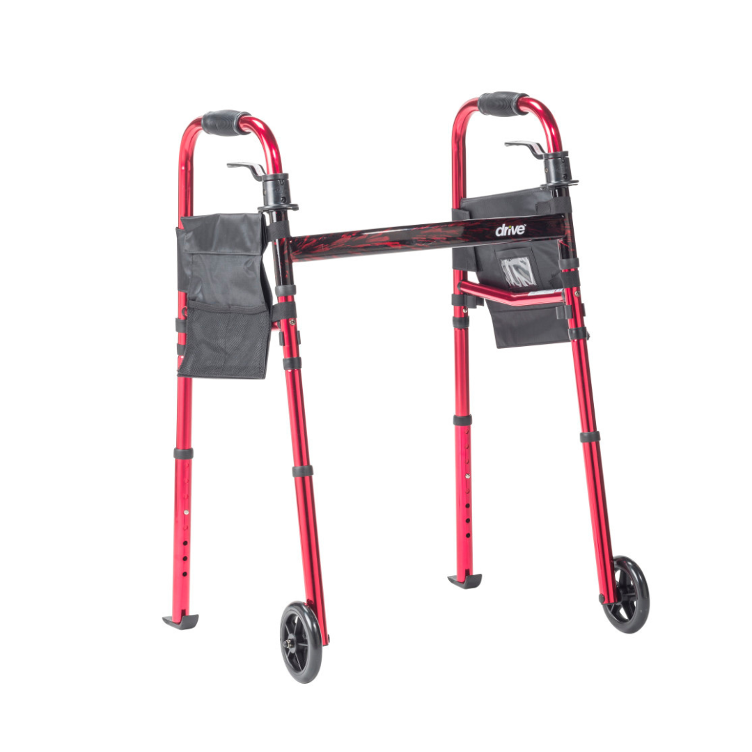 The Drive Deluxe Folding Travel Walker with 5" Wheels features a red frame, adjustable legs, hand grips, two front wheels, and black side pouches—an ideal mobility aid for support and easy storage.