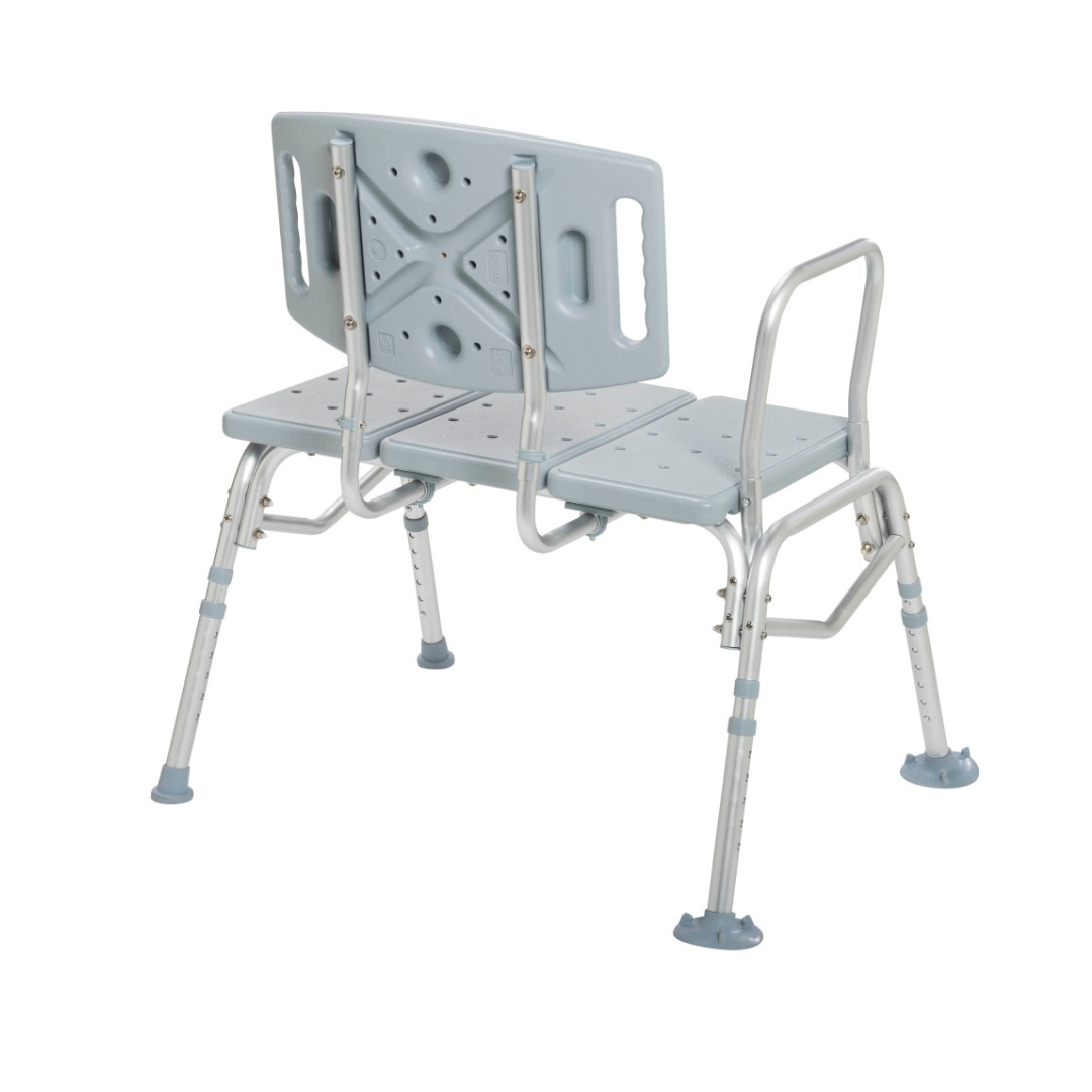 The Drive Bariatric Transfer Bench is a gray, heavy-duty adjustable shower bench with a backrest, two armrests, and four sturdy rubber-tipped legs to aid those with mobility challenges during bathing.