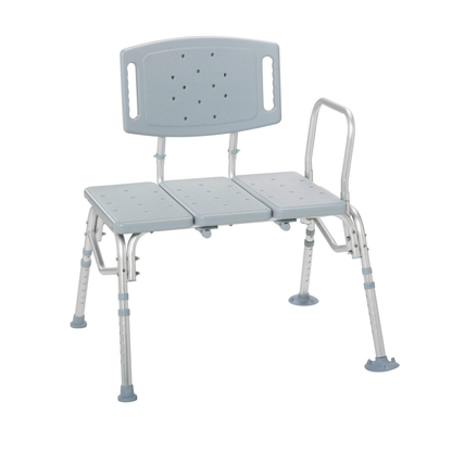 The Drive Bariatric Transfer Bench is a gray and silver heavy-duty bench with a backrest, armrest, and height-adjustable legs with suction tips for stability, designed to assist individuals with mobility challenges during bathing.