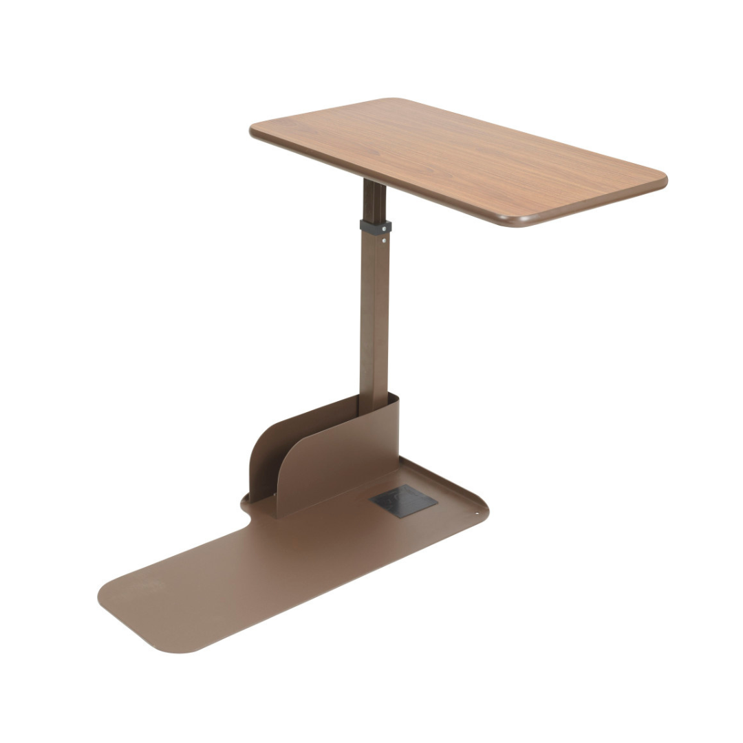 The Drive Couch & Lift Chair Swivel Table is an adjustable brown table with a rectangular woodgrain top and pivoting surface, supported by a single metal column on a flat base that slides easily under beds or lift chairs.
