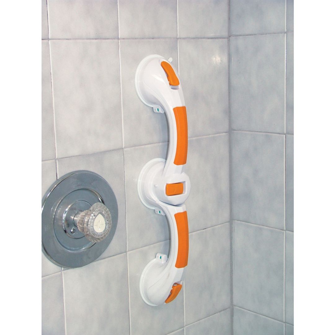 A Drive Shower Rotating Suction-Cup Grab Bar in white and orange with a non-slip grip is mounted vertically on a tiled shower wall beside a metal handle and knob.