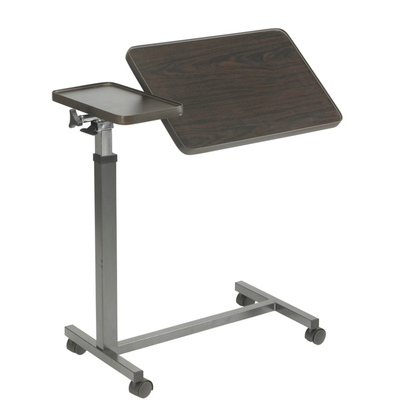 The Drive Overbed Table with Double Top & Tilt features a dark woodgrain tilting main surface, a smaller flat left side tray, and a sturdy metal base with four caster wheels for easy mobility.