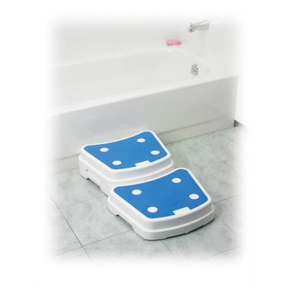 Two Drive Portable Bath Step stackable bathtub safety steps, in white and blue, are placed in front of a tub in a tiled bathroom to enhance safety when entering or exiting the bathtub.