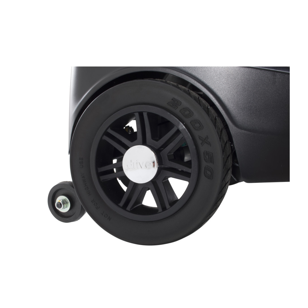 Close-up of a large black wheel with a silver center attached to the Drive Scout Compact 3-Wheel Scooter, with a smaller stabilizing wheel on the left.