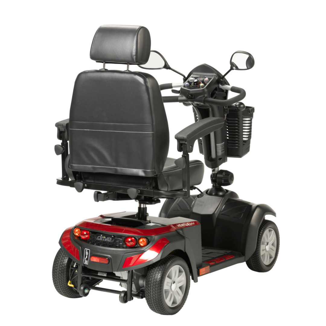 A Drive Ventura 4-Wheel HD Bariatric Scooter with a padded black seat, armrests, and headrest is shown from the rear, featuring rear lights, a storage basket, and a red and black color scheme.