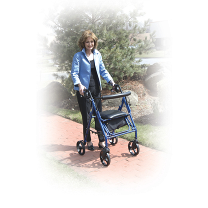 A woman in a blue jacket uses the Drive Hybrid Duet Rollator/Transport Chair on a red brick path outdoors, surrounded by trees and shrubs.