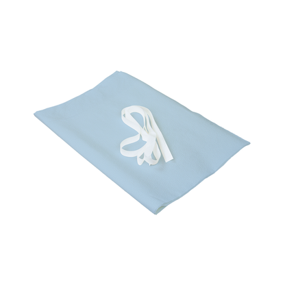 A Dynarex Exam Gown - Disposable Patient Gown, light blue and folded with a white tie on top, displayed on a plain white background.