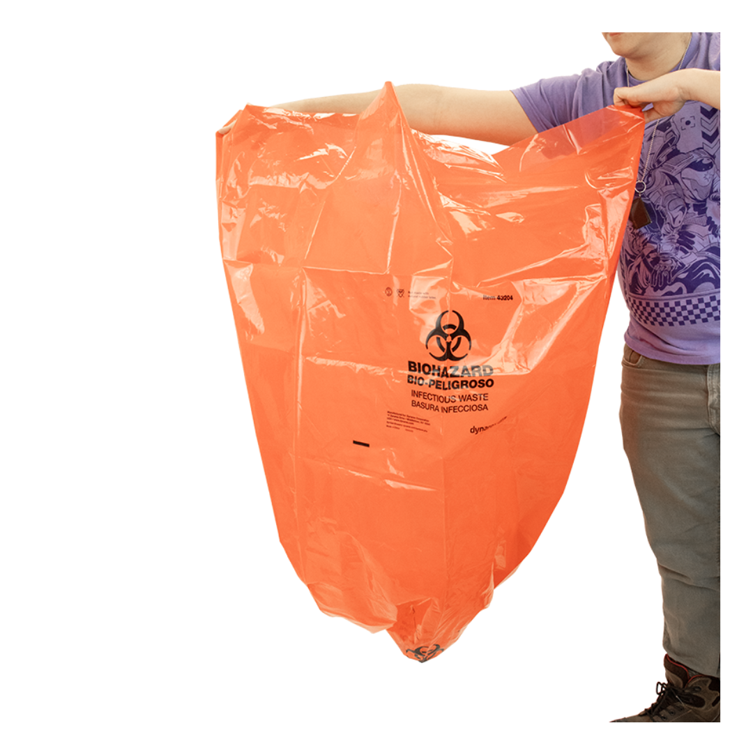 A person holds open a large orange Dynarex Biohazard Waste Bag labeled for infectious waste with biohazard symbols and bilingual text, obscuring the top of their face from view.