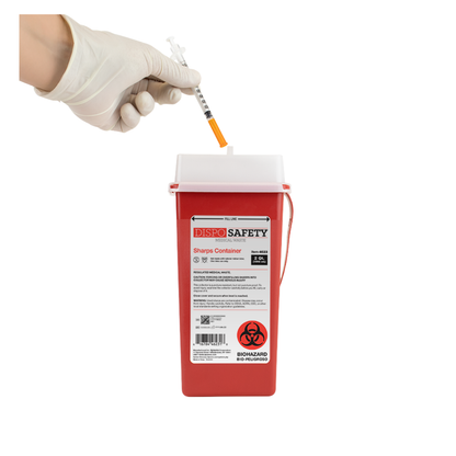 A gloved hand drops a used syringe into a red Dynarex Sharps Containers unit labeled DISPO SAFETY, ensuring safe disposal of sharps against a white background.