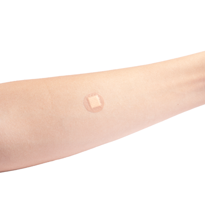 A close-up of a forearm shows a small, square Dynarex Sheer Plastic Adhesive Bandage - Sterile applied to the skin, suggesting a recent injection or blood test.
