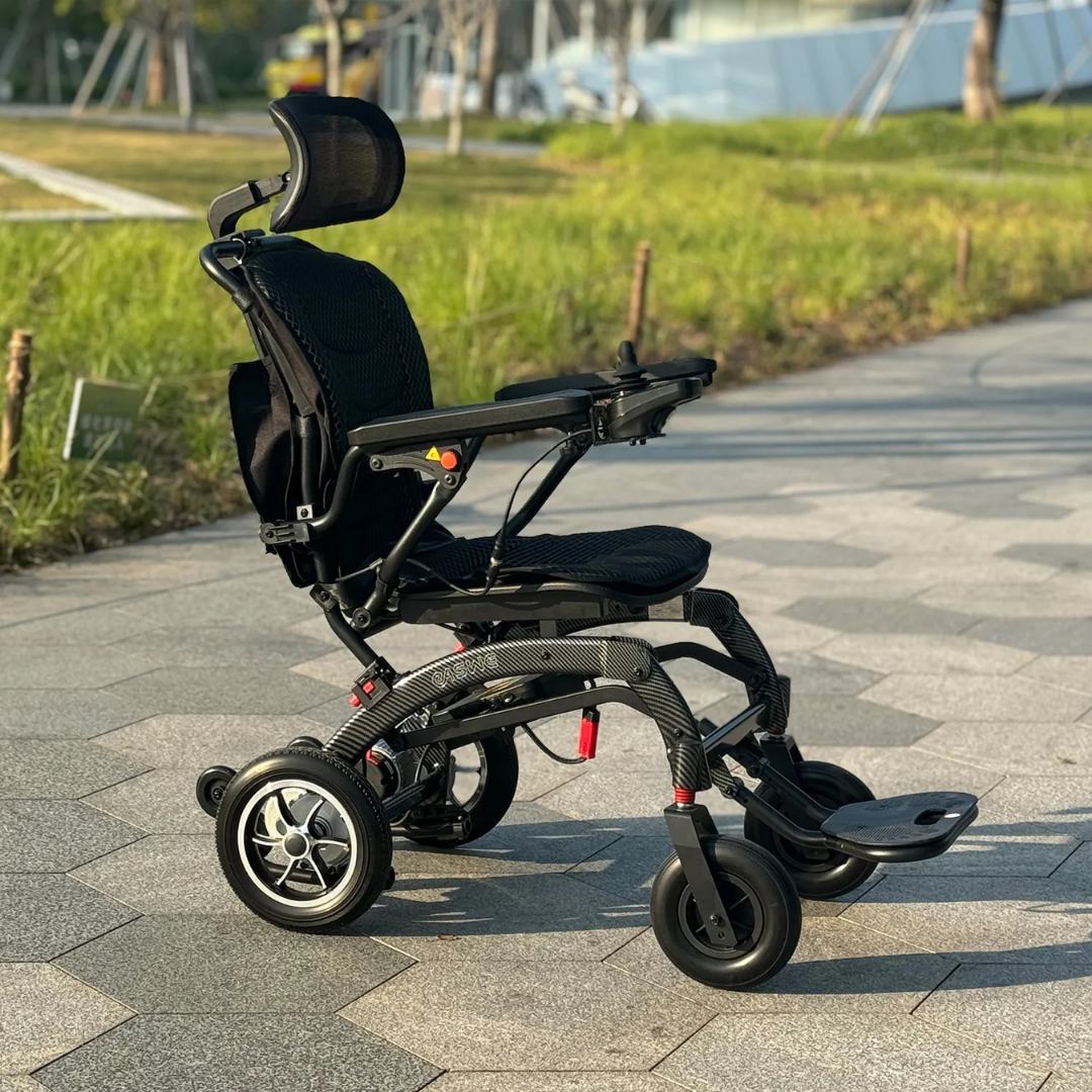 The EASWE B10 Portable Folding Powerchair—an airline-approved, modern electric wheelchair with dual motors and a mesh seat—is parked on a sunlit paved path surrounded by green grass.