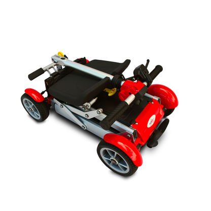 The EV Rider Gypsy Ultra Compact Airline Approved Scooter in red is shown folded for transport, displaying its four wheels, handlebars, and metal frame against a white background.