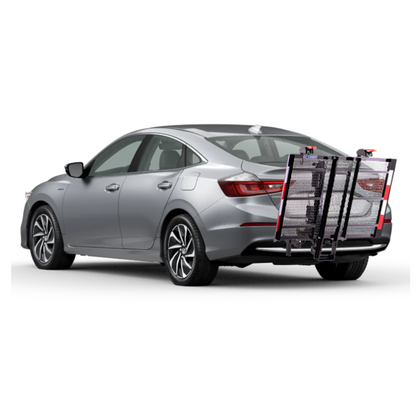 A silver sedan with an EZ-Carrier Electric Lift – Manual Fold Up (Semi-Auto) attached to the rear, featuring a metal cargo carrier, foldable ramp, and red safety reflectors. Check specs or watch videos for more details.