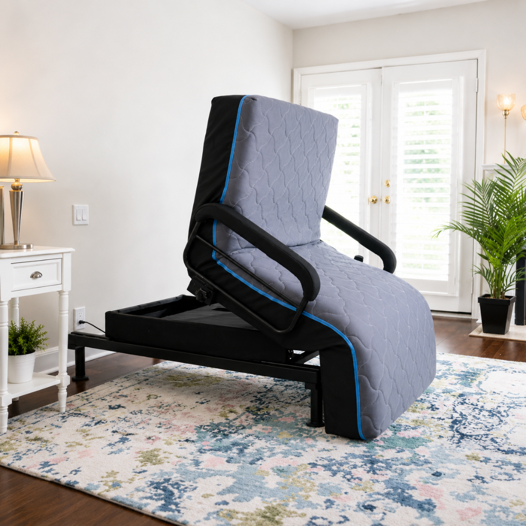The EZLift Bed™ - Sleep To Stand Bed in gray with black handrails stands upright in a bright room with a floral rug, white side table, lamp, potted plant, and French doors—ideal for regaining independence and comfort.