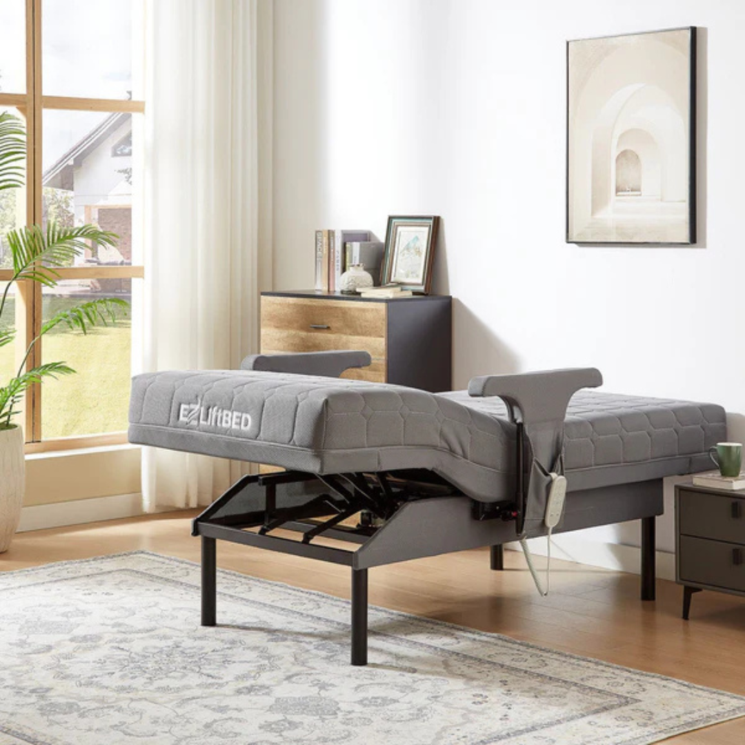 An EZLift Bed™ - Deluxe Sleep To Stand Electric Bed with a gray mattress stands elevated in a bright, stylish bedroom with a rug, nightstand, dresser, wall art, and sunlight streaming through sheer curtains.