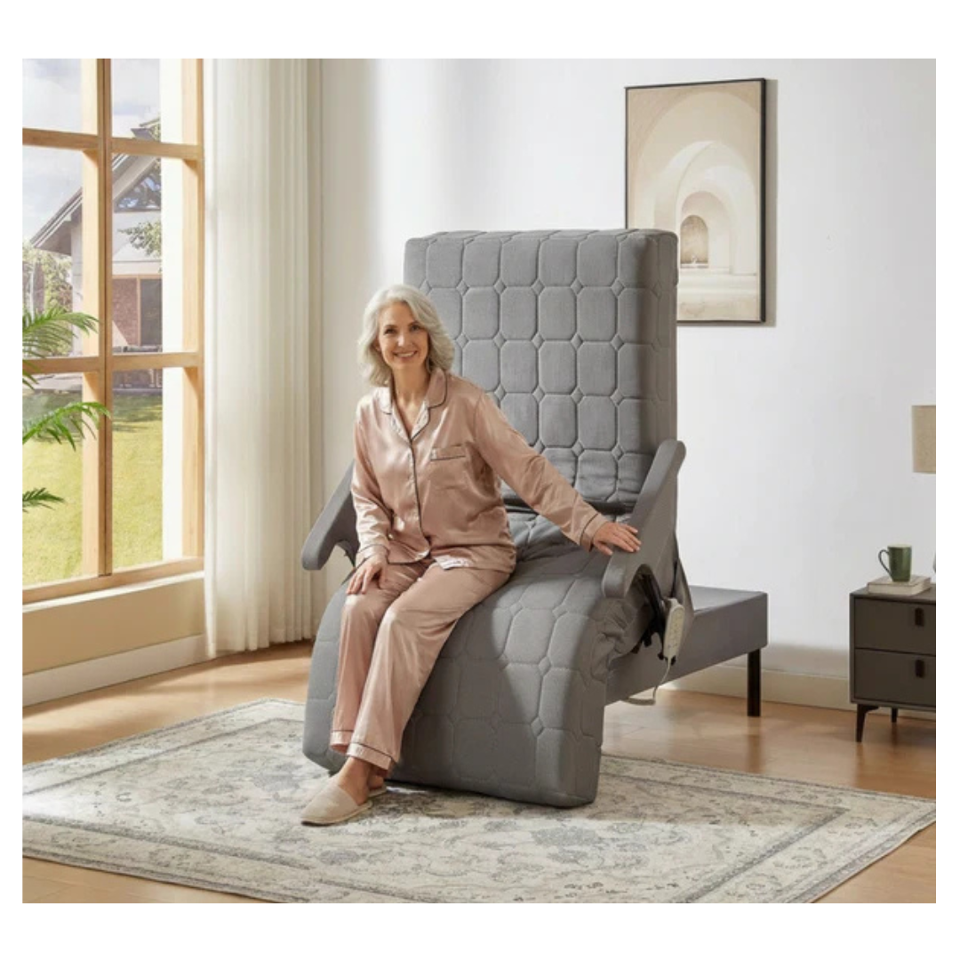 An older woman in beige pajamas smiles as she relaxes on the EZLift Bed™ - Deluxe Sleep To Stand Electric Bed, highlighting the comfort and independence this adjustable electric bed brings to any bright living room.