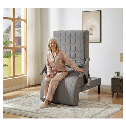 An older woman in beige pajamas smiles as she relaxes on the EZLift Bed™ - Deluxe Sleep To Stand Electric Bed, highlighting the comfort and independence this adjustable electric bed brings to any bright living room.