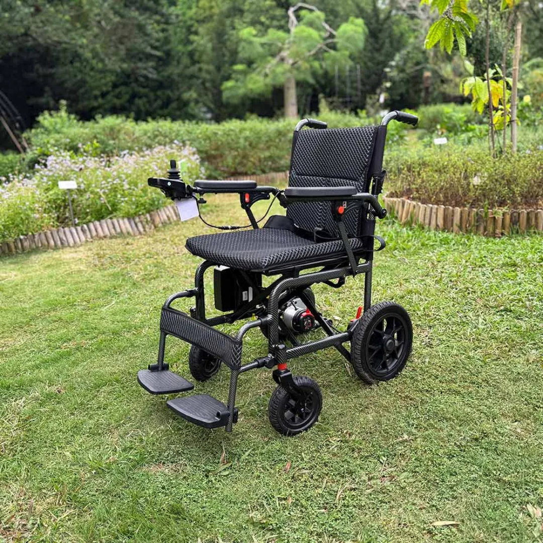 An Easwe™ D10 Foldable Electric Wheelchair - FAA Approved, featuring a lightweight black frame and mesh seat, sits empty on green grass in a park with trees, plants, and a wooden fence in the background.