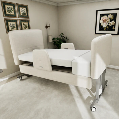 An Elevra Deluxe Rotating Hi-Lo Lift Assist Bed with cream upholstery sits in a bright bedroom, highlighted by framed floral art and a potted plant. Raised head, foot, and side panels enhance comfort.