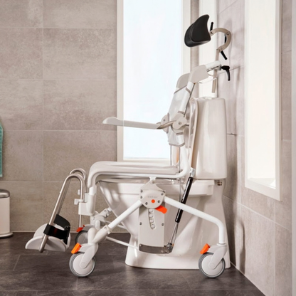 An Etac Swift Mobil Tilt-2 tilt-in-space mobile shower commode chair positioned over a toilet in a bathroom.