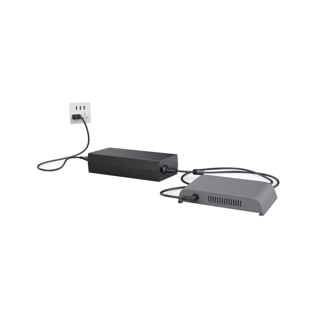 An External Battery Charger for TOC3 Rhythm O2 Concentrator is plugged into a wall outlet and connected to a gray TOC3 device with vents, both resting on a white surface.