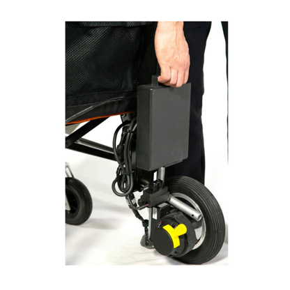 A hand is holding a rectangular battery pack attached to the side of the Feather Powerchair—an ultralight, travel-approved electric wheelchair weighing only 33 lbs—near its front wheel’s motorized component.