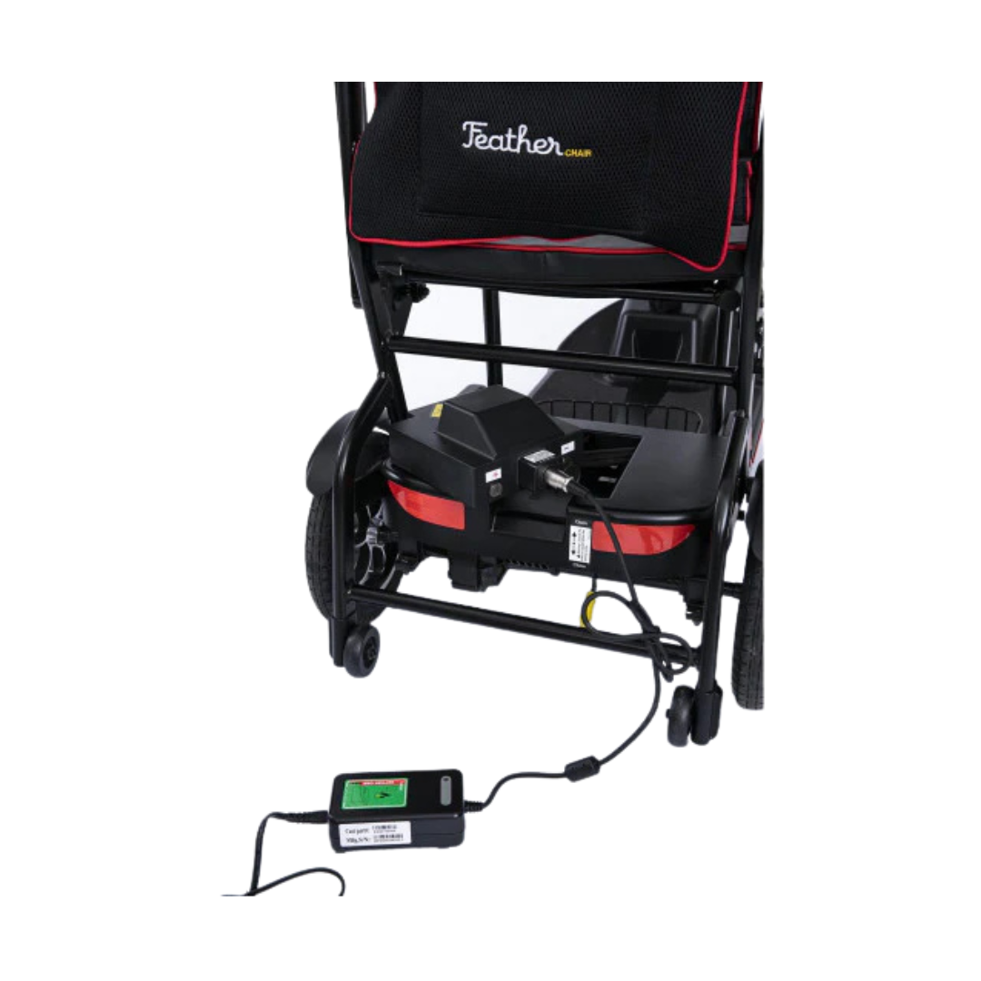 Rear view of the Feather Ultralite Portable Scooter (only 37 lbs) with its battery pack plugged into a charger and electrical outlet, showcasing the convenient charging of this lightest portable mobility scooter.
