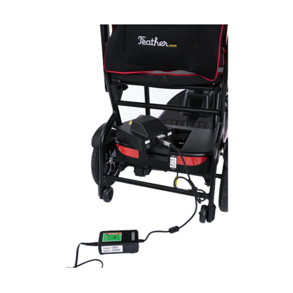 Rear view of the Feather Ultralite Portable Scooter (only 37 lbs) with its battery pack plugged into a charger and electrical outlet, showcasing the convenient charging of this lightest portable mobility scooter.
