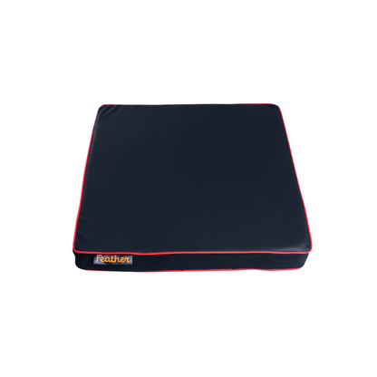A square, dark-colored Feather Portable Cushion with red piping, a front label reading "Feather," and a convenient handle is shown on a plain white background.