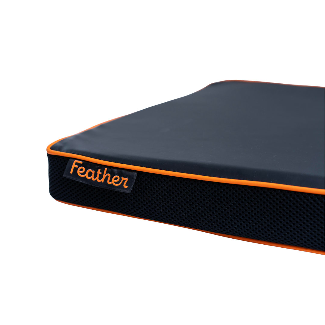 A close-up of the Feather Portable Cushions—an all-purpose, dark cushion with orange piping, water-resistant material, handle, and a Feather tag on the side—shown against a white background.