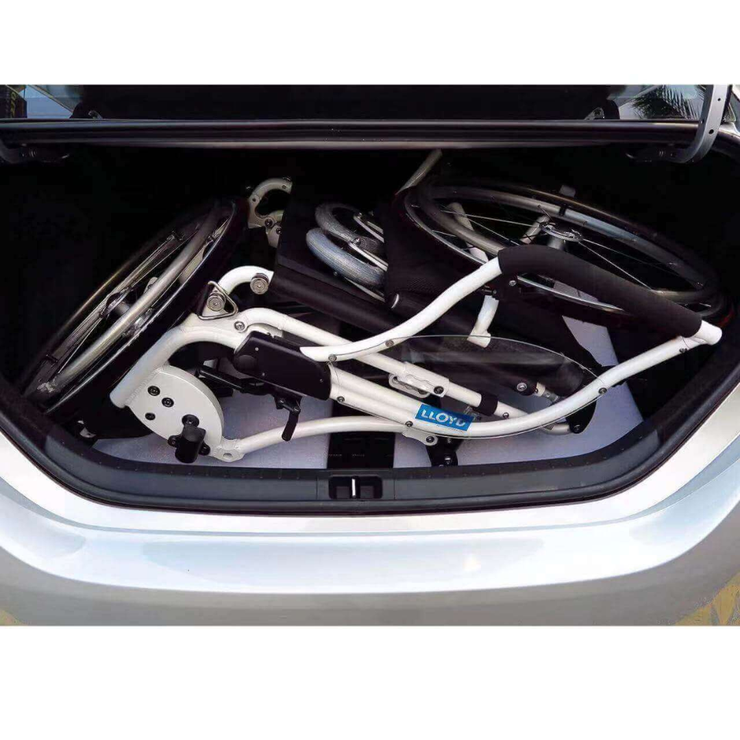 A Foldawheel Lloyd LEO Ultralite Standing Manual Wheelchair is folded and placed in a car trunk, showing its compact design and easy fit within the available space.