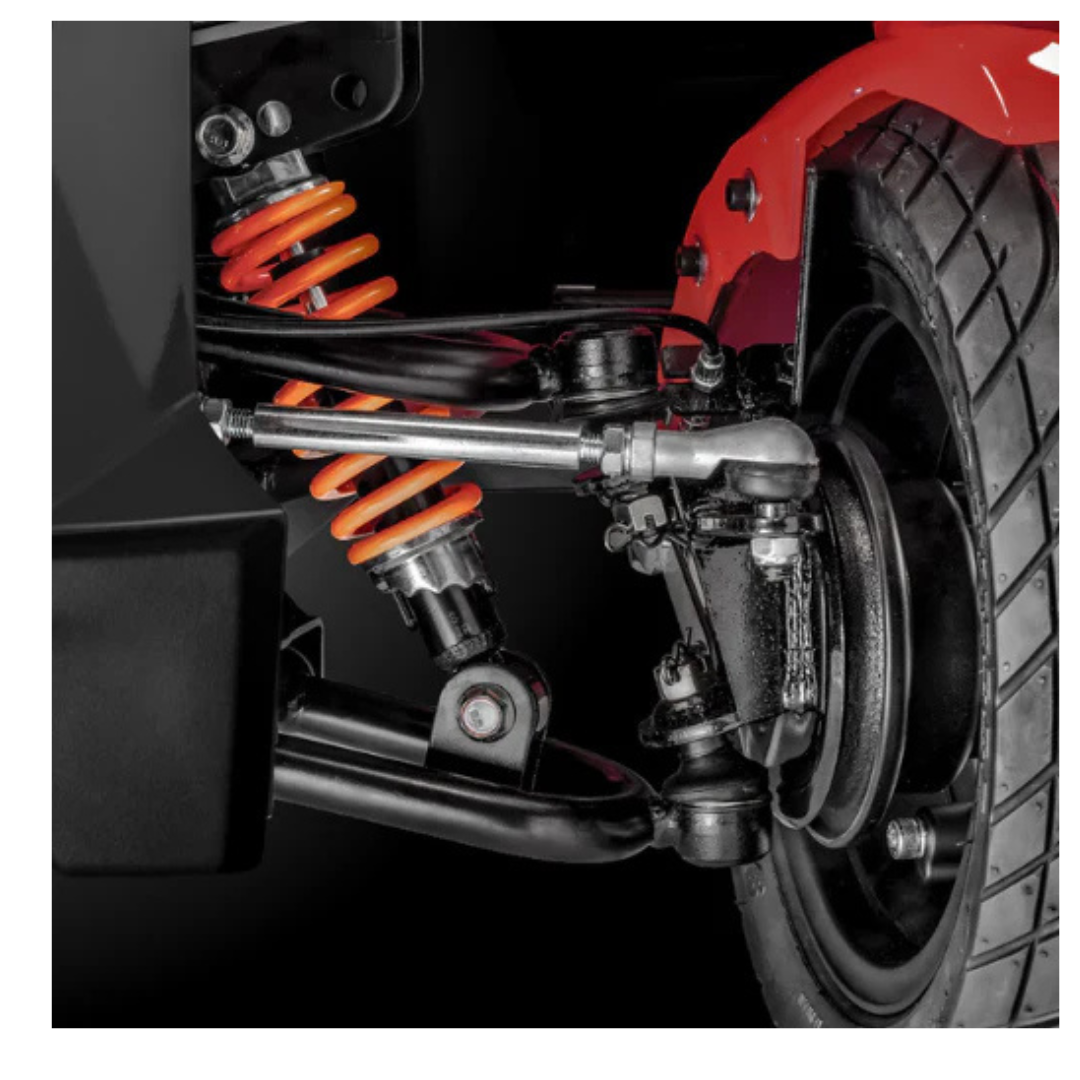 Close-up of the FreeRider FR1 Terrain Heavy Duty Mobility Scooter’s front suspension system, featuring an orange coil spring, shock absorber, control arms, and wheel—highlighting sporty performance and enhanced handling with a double wishbone design.