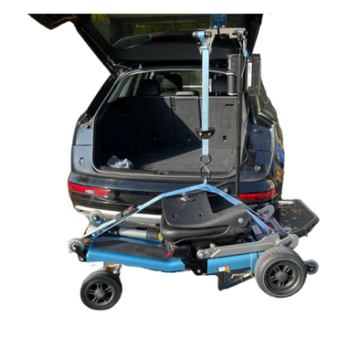 A FreeRider Scooter Lift For Vehicles, attached to the open trunk of a black SUV, holds a mobility scooter suspended and ready for loading or unloading.