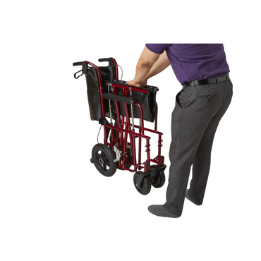 A person in a purple shirt and gray pants folds the Medline Freedom Plus Lightweight Bariatric Transport Chair with black handles and backrest. This portable design, featuring large rear wheels, smaller front wheels, and easy-to-use hand brakes, rests against a white background.
