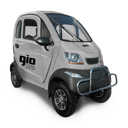 The compact white GIO Golf Fully Enclosed Mobility Scooter features a sleek, scooter-like design with a silver grille and two doors. Small wheels and logos enhance its charm against a white background, showcasing its effortless style.