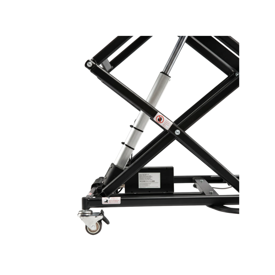 Close-up of the ComfyGo GO-Lift Portable Lift for Electric Wheelchairs and Scooters, showing its black metal scissor lift mechanism with a visible hydraulic cylinder, caster wheel, and warning labels, isolated on a white background.