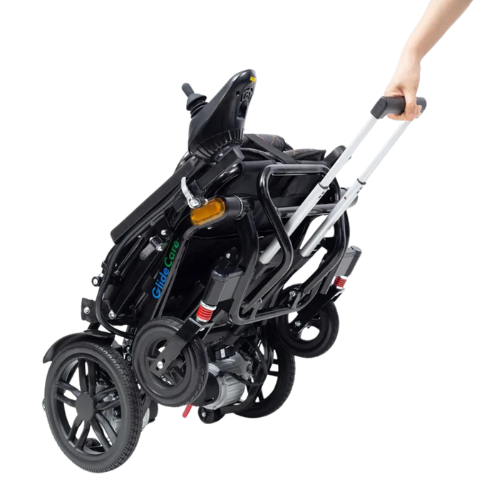 A person pulls the compact, folded Glide Care G-5 Lightweight Foldable Electric Wheelchair by its extended handle, highlighting its easy portability and travel-friendly design.