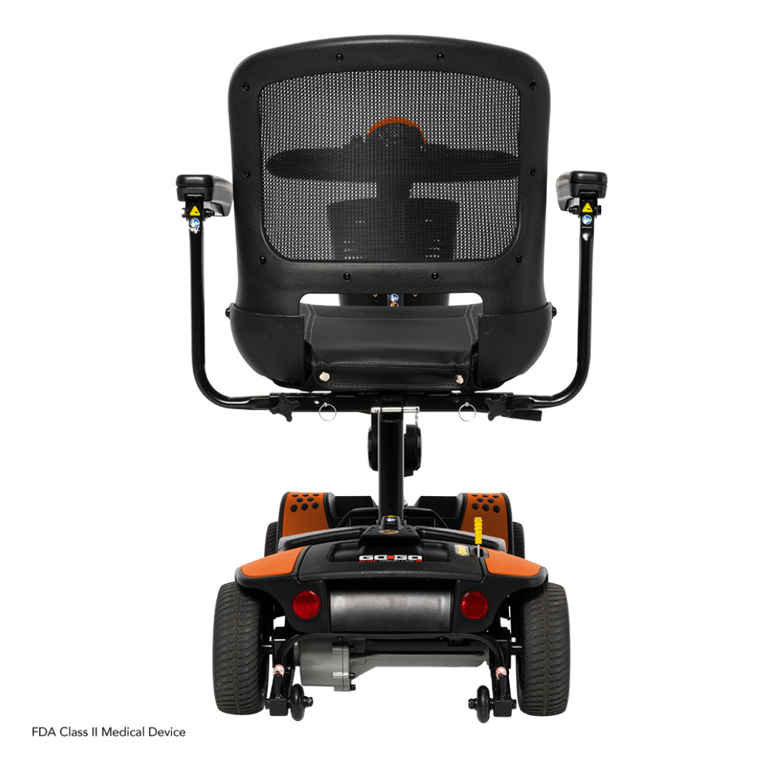 Rear view of the Pride Mobility Go Go Elite Traveller® 2 Platinum Scooter, a compact travel scooter featuring EZ Turn technology, mesh backrest, black frame with orange accents, and armrests. Shown on a white background.