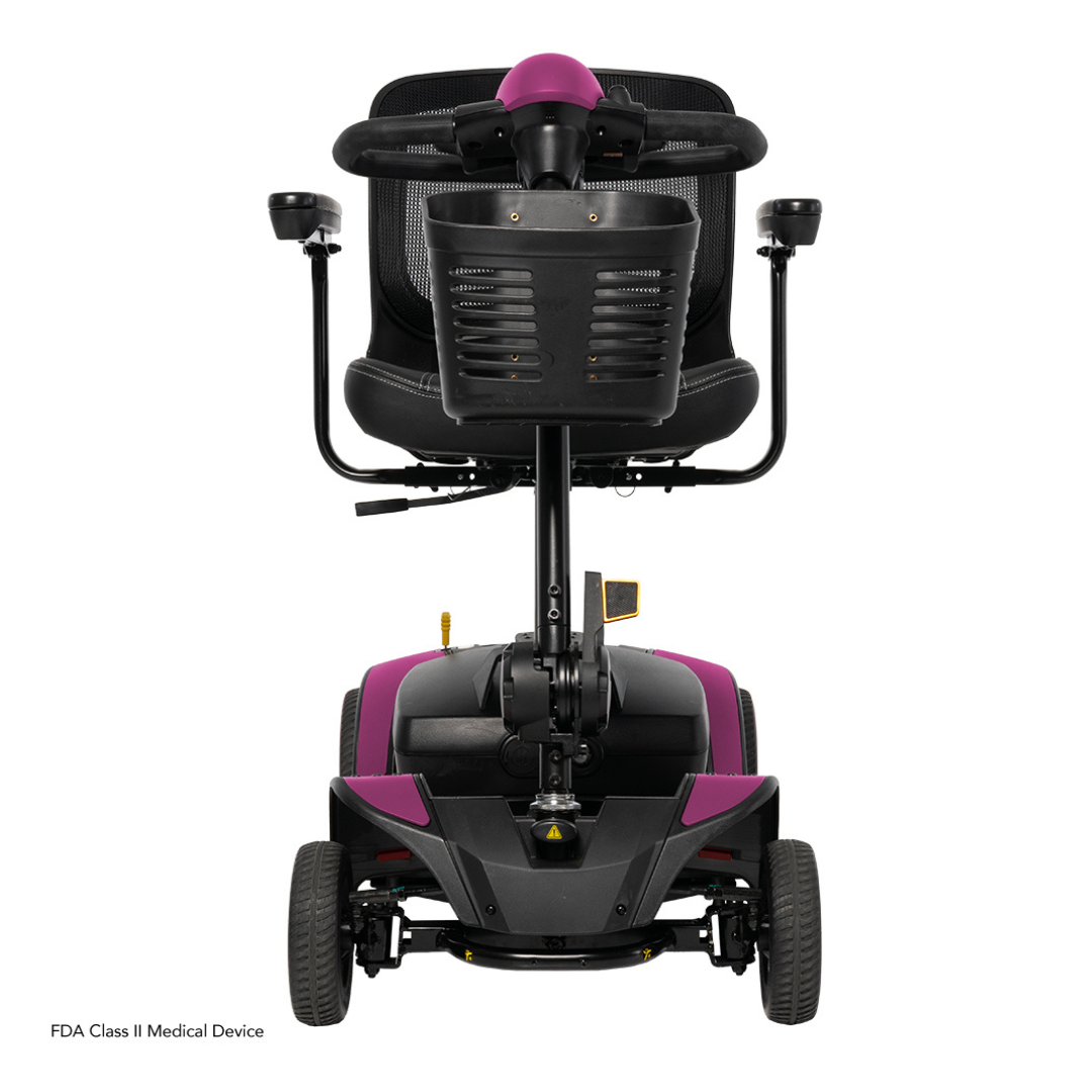 Rear view of the Pride Mobility Go Go Elite Traveller® 2 Platinum Scooter with black seat, armrests, magenta accents on handle and body, four wheels. FDA Class II Medical Device label visible in the corner.