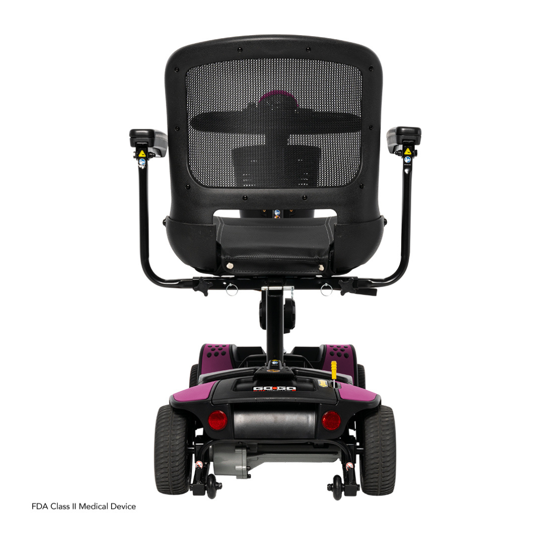 Rear view of the Pride Mobility Go Go Elite Traveller® 2 Platinum Scooter, featuring a black mesh backrest, armrests, four wheels, stylish purple accents, and an FDA Class II medical device label.