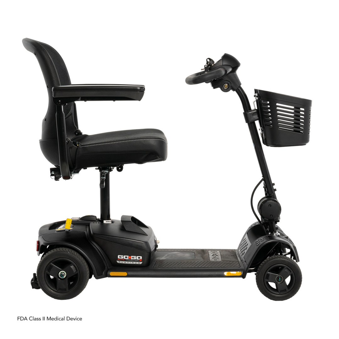 The Pride Mobility Go Go Elite Traveller® 2 Platinum Scooter is a sleek black travel scooter with EZ Turn technology, padded seat, armrests, handlebars, control panel, and front basket—compact and designed for personal mobility.