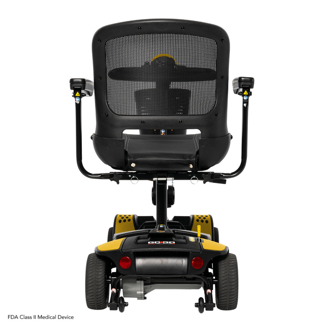 Rear view of the Pride Mobility Go Go Elite Traveller® 2 Platinum Scooter in black and yellow, featuring a mesh backrest, armrests, four wheels, and an exposed control panel. Its compact build suits both indoor and outdoor use.