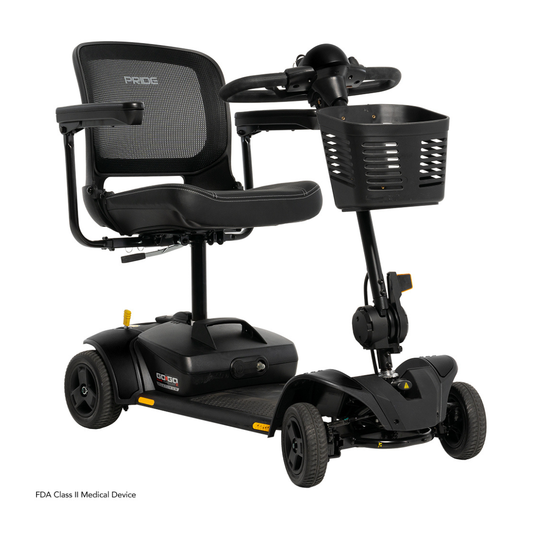 The Pride Mobility Go Go Elite Traveller® 2 Platinum Scooter is a black, three-wheel travel scooter with EZ Turn technology, mesh backrest, armrests, and front storage basket. This compact FDA Class II device is displayed on a white background.