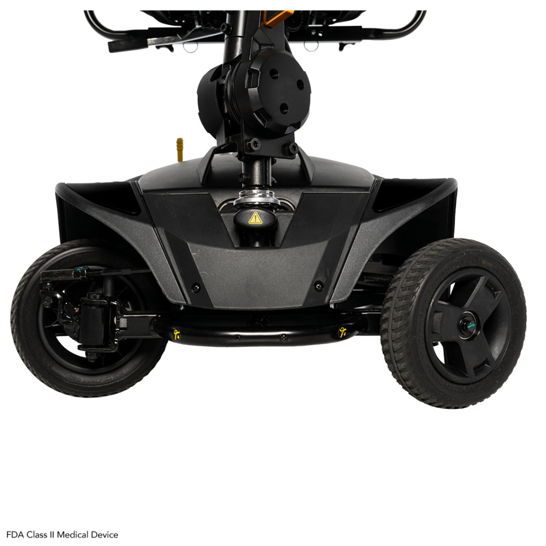 Close-up of the front wheels and base of the Pride Mobility Go Go Elite Traveller® 2 Platinum Scooter, highlighting wheel suspension, EZ Turn technology, steering mechanism, and an FDA Class II Medical Device label at bottom left.