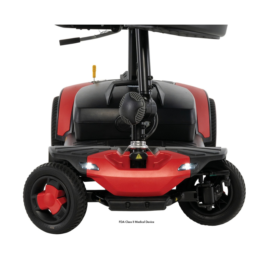 Front view of a red and black Pride Go Go® Elite Traveller Gen 3 Scooter, showing the front wheels, LED headlights, and floorboard.