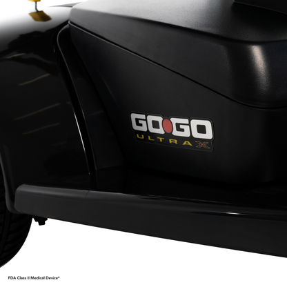 Close-up of the black Pride Mobility Go Go® Ultra X 3-Wheel Scooter with its FDA Class II Medical Device* label at the bottom left. Renowned for its portable design, this economical scooter perfectly combines convenience and affordability.