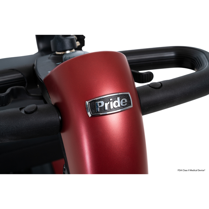 A close-up of the handlebars on a red Pride Mobility Go Go® Endurance Li 4-Wheel Scooter shows steering controls with a metallic finish and the Pride logo. FDA Class II Medical Device is displayed in the lower right corner. Comfort-Trac Suspension ensures an exceptionally smooth ride.