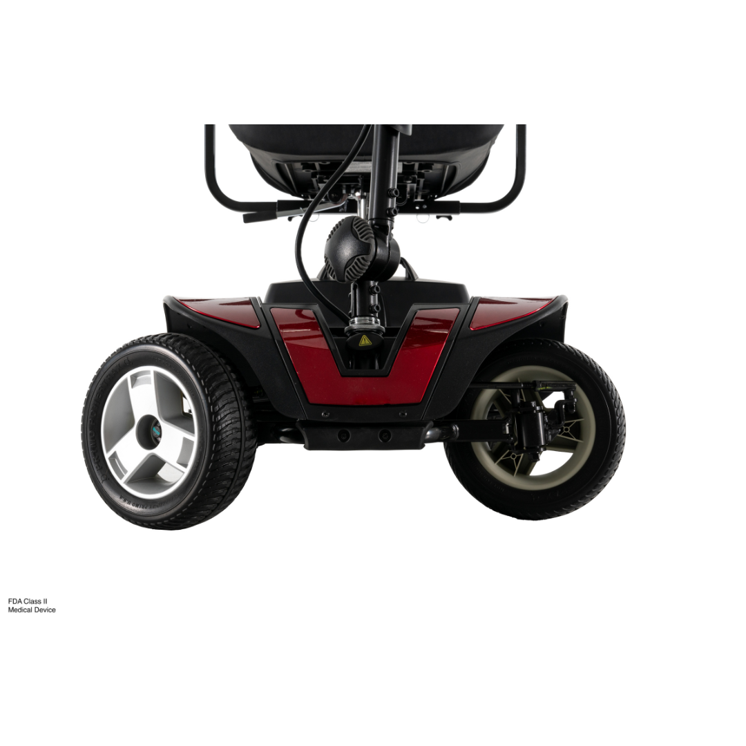 Close-up of the front wheels and lower frame of the red Pride Go Go® Sport 4-Wheel Scooter, showing its suspension, tires, and part of the seat. Shot on a white background, perfect for responsive grid layouts.