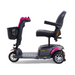 The Golden Buzzaround LX GB119 is a premium 3-wheel portable mobility scooter that boasts a modern design with its sleek black seat and handlebars, highlighted by pink accents on the stem and wheel covers. The silver and black wheels enhance its stylish, compact form, while the included front basket adds functional convenience.