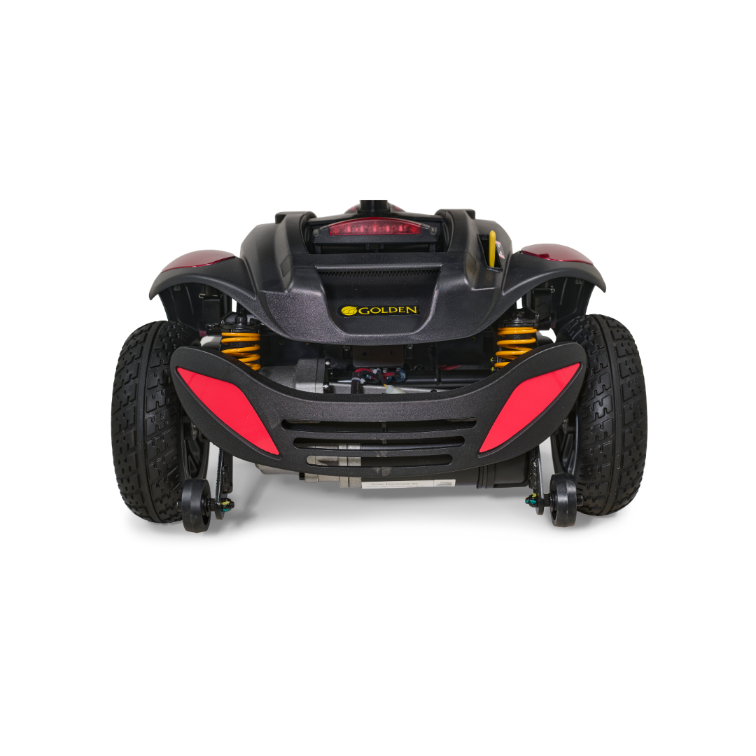 A luxury mobility scooter, the Golden Buzzaround LX GB119 - Heavy Duty 3 Wheel Portable Mobility Scooter, is shown from the front with large tires, red accents, and yellow suspension springs. The brand name Golden is prominently displayed on its sleek body.